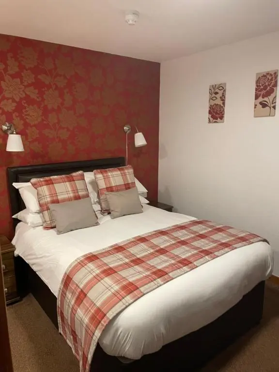 a bedroom with a large bed with a plaid blanket at Royston Guest House Inverness in Inverness