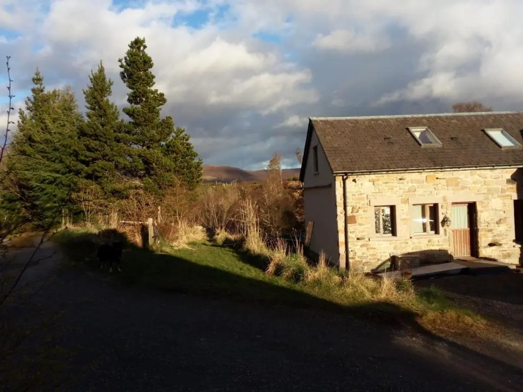 an old stone house sitting on the side of a road at Sunrise House in Inverfarigaig
