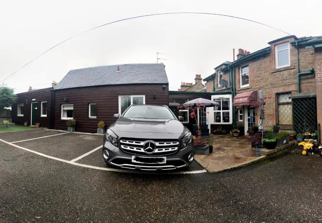a car parked in a parking lot in front of a house at Carisbrooke Guest House in Inverness