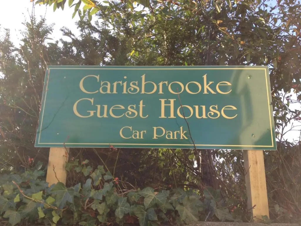 a green sign for a guest house car park at Carisbrooke Guest House in Inverness