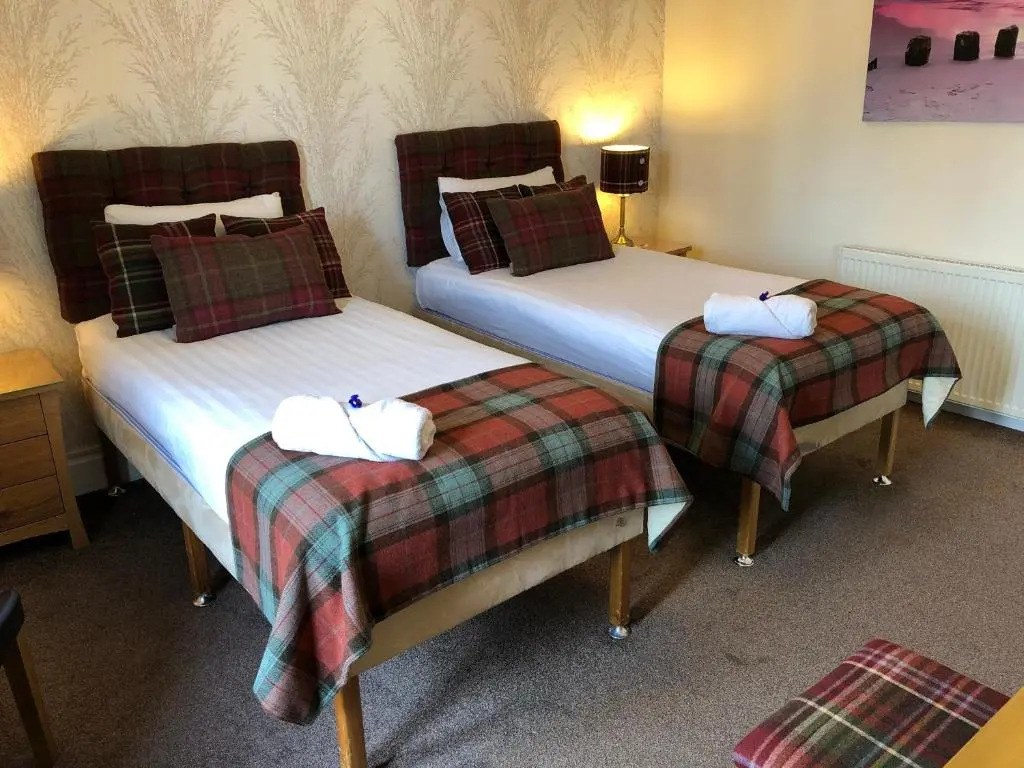 two beds in a hotel room with towels on them at Carisbrooke Guest House in Inverness
