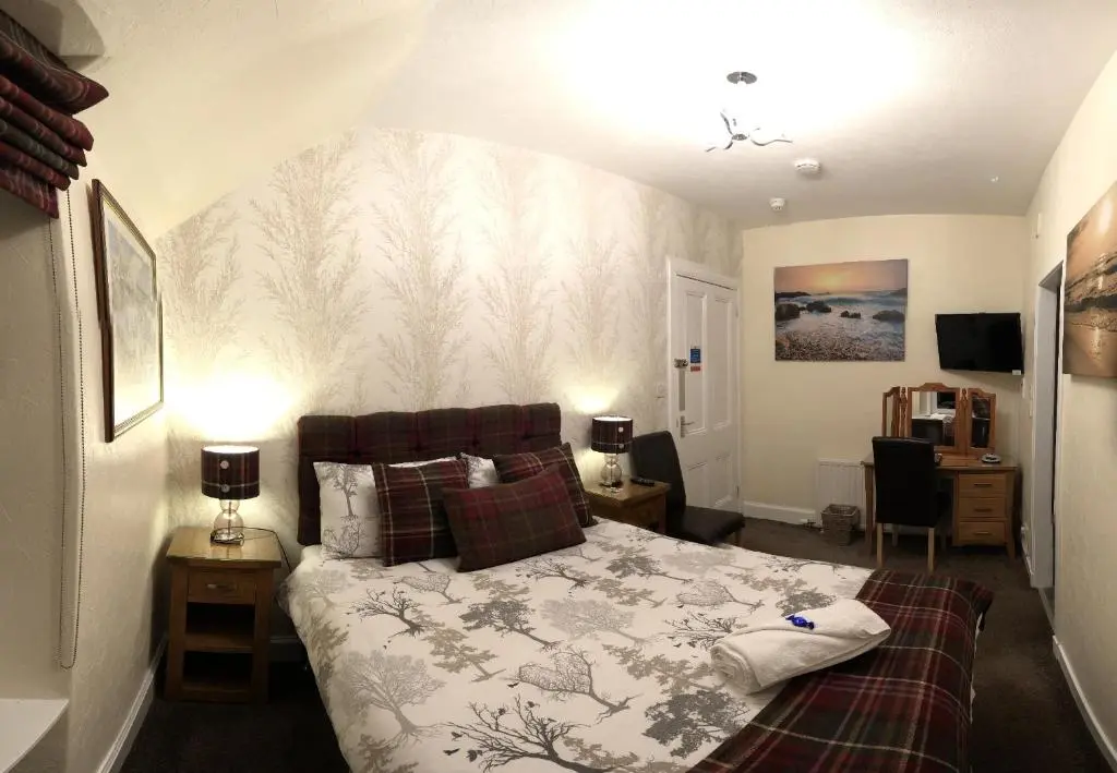 a bedroom with a bed and two lamps and a desk at Carisbrooke Guest House in Inverness