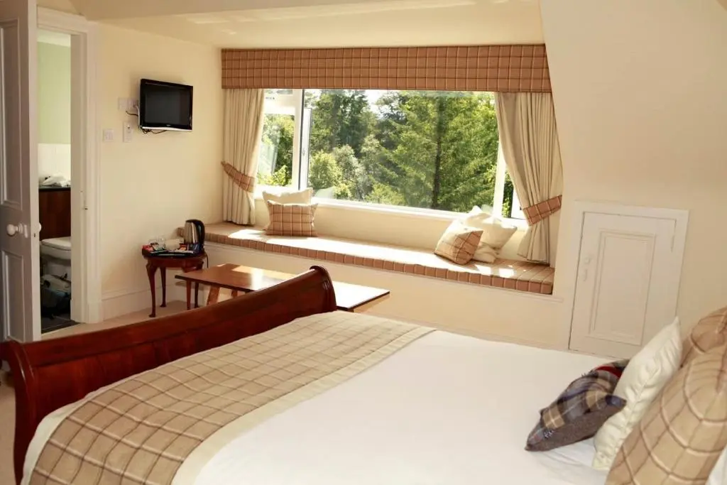 a bedroom with a bed and a large window at Tor-Na-Coille Hotel in Banchory