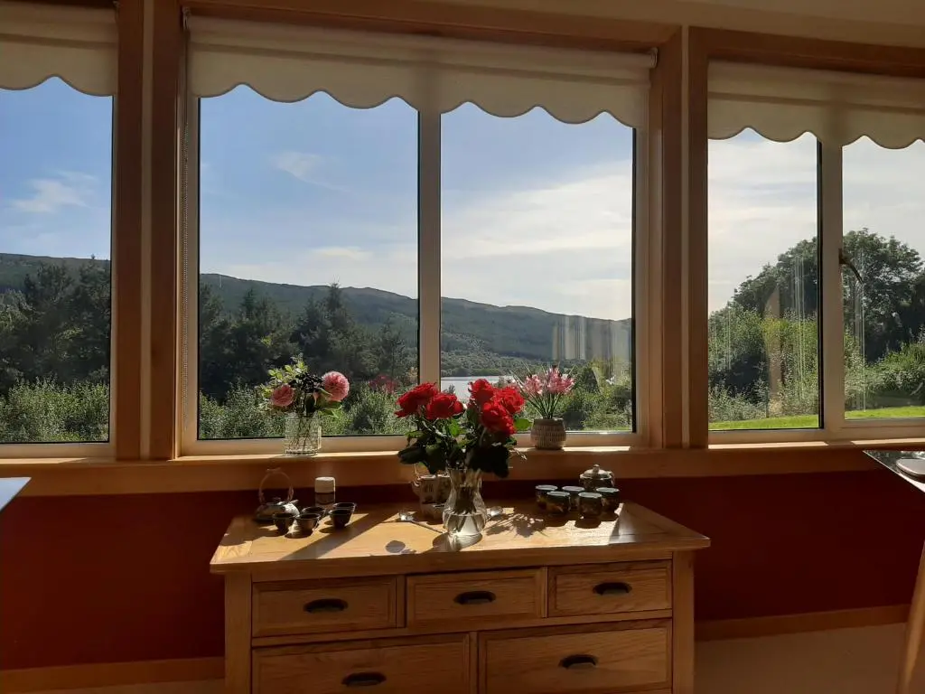 a room with windows and a table with flowers on it at High March in Drumnadrochit