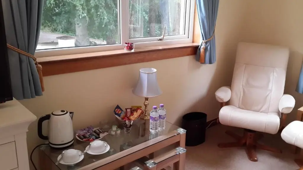 a table with a lamp and a chair in a room at High March in Drumnadrochit