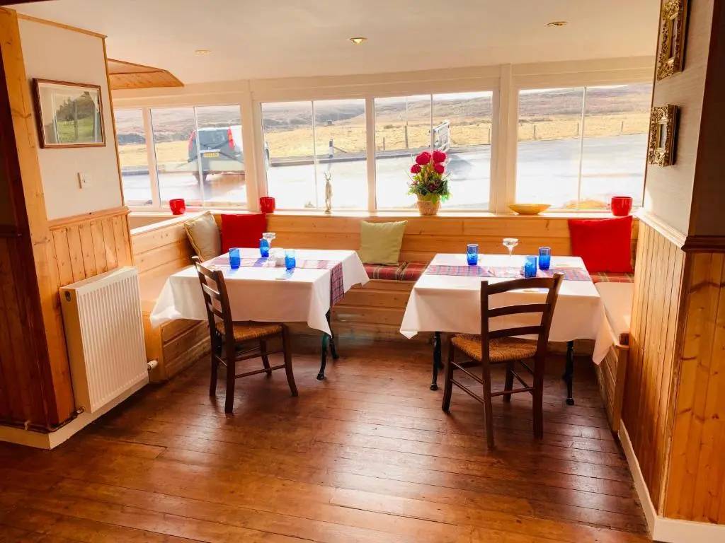 a restaurant with two tables and chairs in a room at Aultguish Inn in Garve