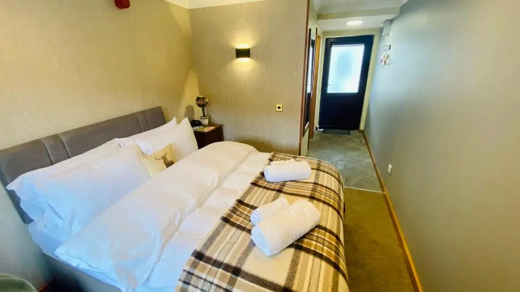 a hotel room with a bed with white sheets at Aultguish Inn in Garve