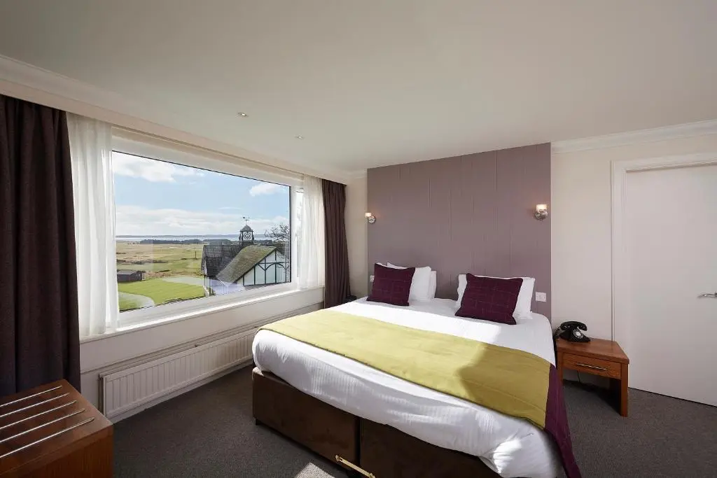 a bedroom with a bed and a large window at Royal Golf Hotel, by Highland Coast Hotels in Dornoch