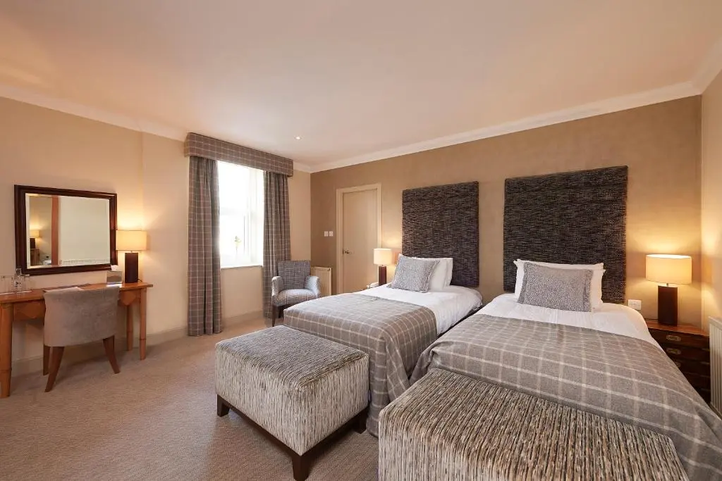 a hotel room with two beds and a desk at Royal Golf Hotel, by Highland Coast Hotels in Dornoch