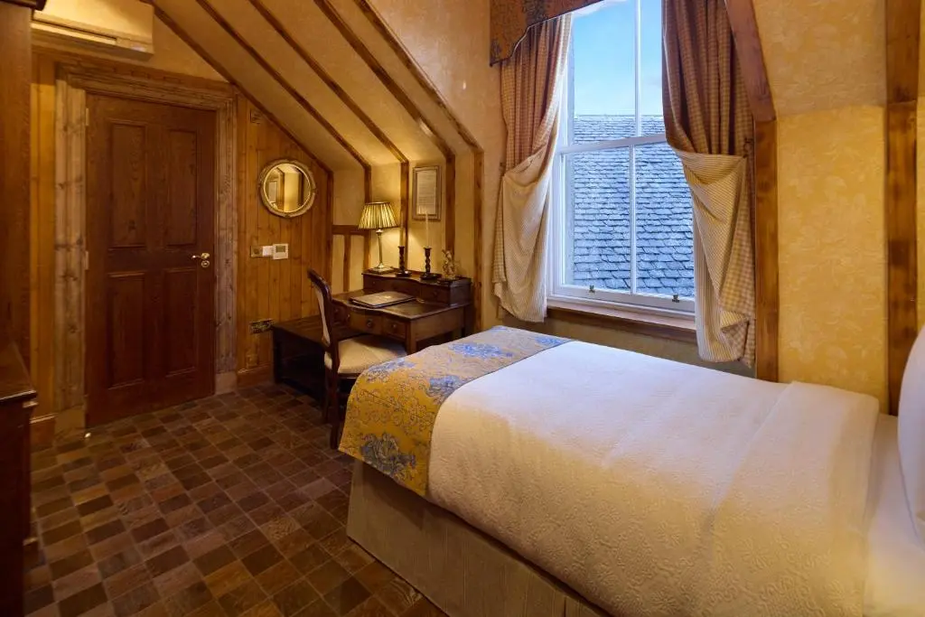 a bedroom with a bed and a desk and a window at The Ambassador Hotel in Inverness