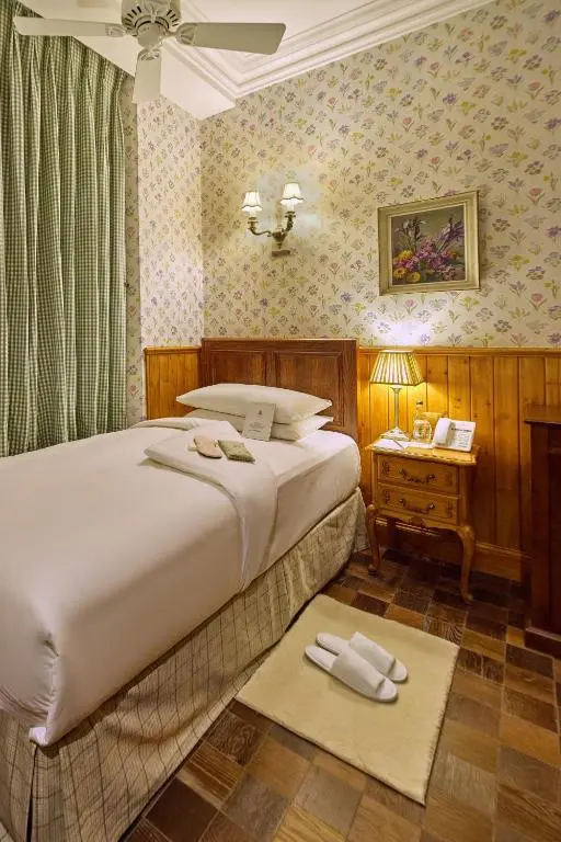 a bedroom with a bed and a table with a lamp at The Ambassador Hotel in Inverness