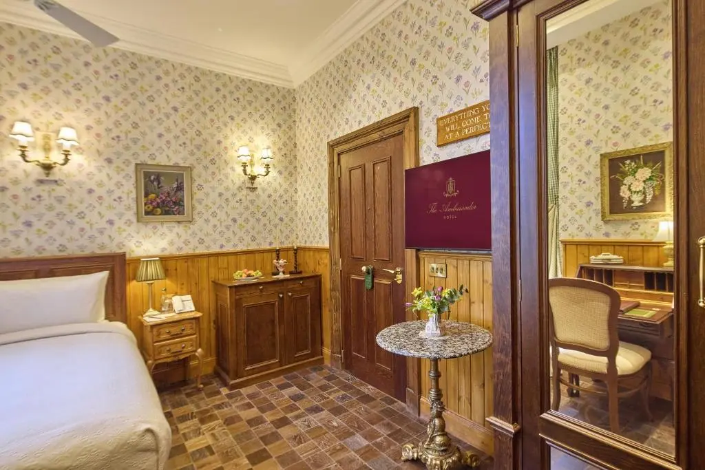 a bedroom with a bed and a table and a chair at The Ambassador Hotel in Inverness