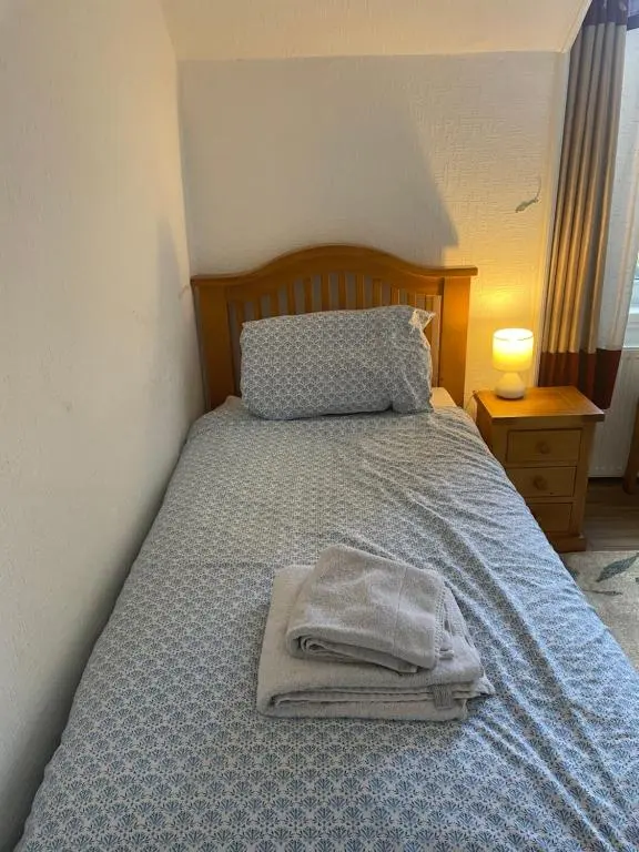 a bed with a blue comforter and two towels on it at Strathallan B&B in Inverness