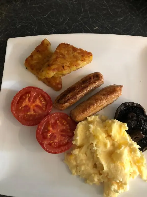a plate of food with eggs sausage and tomatoes at Strathallan B&B in Inverness
