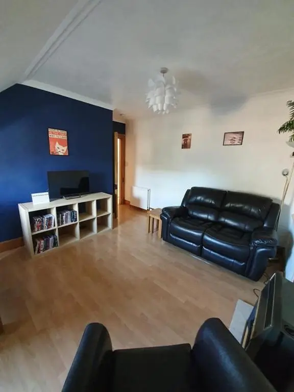 a living room with a black leather couch and a television at Strathallan B&B in Inverness