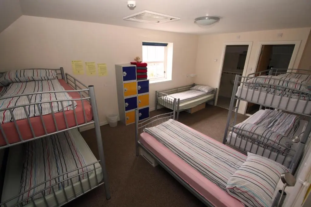 a room with three bunk beds and a window at Ballater Hostel in Ballater