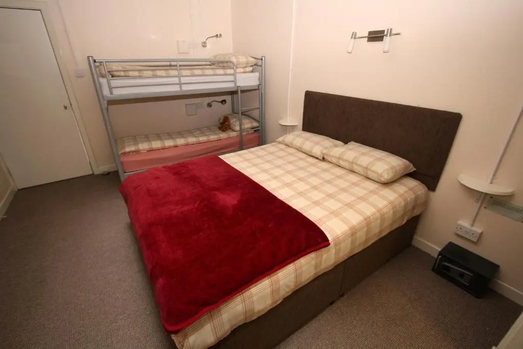 a bedroom with a bed with a red blanket on it at Ballater Hostel in Ballater