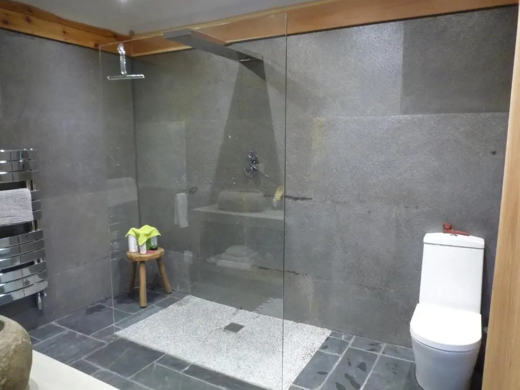 a bathroom with a glass shower with a toilet at Caledonian Cabin in Invergarry