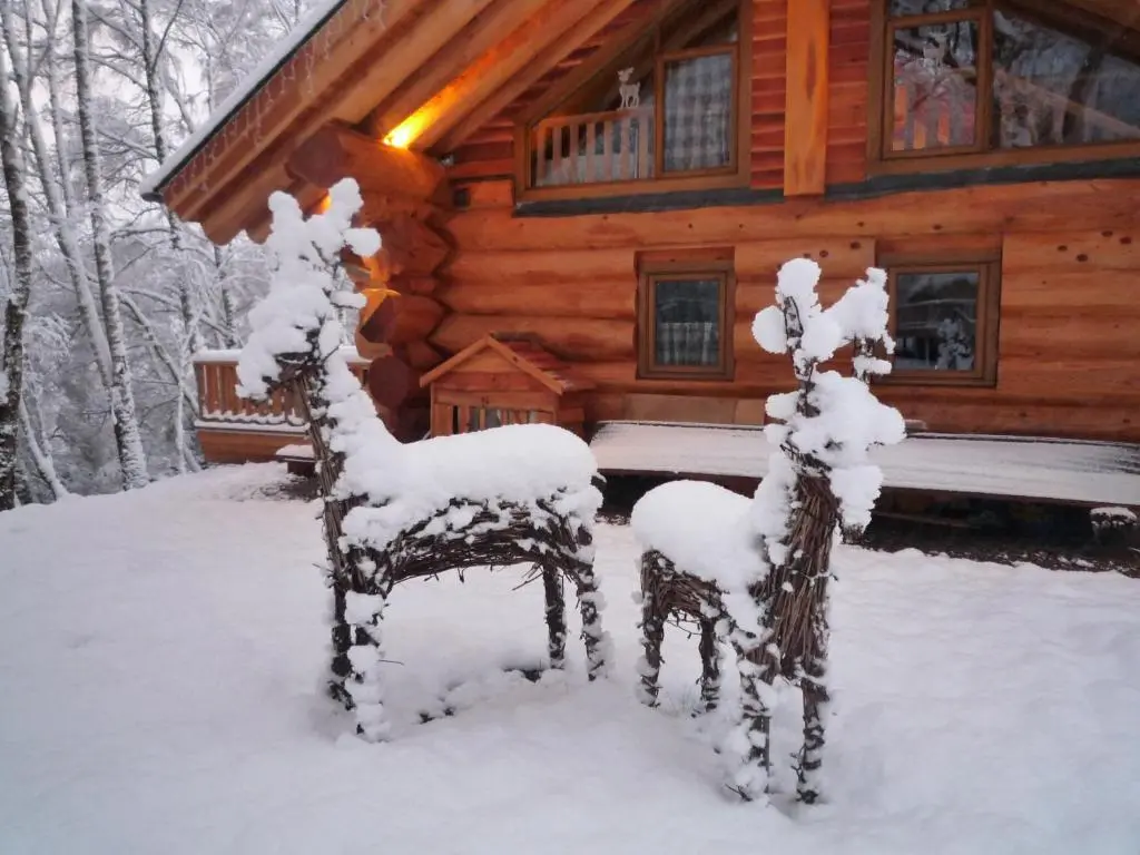 a log cabin in the snow with two chairs at Caledonian Cabin in Invergarry