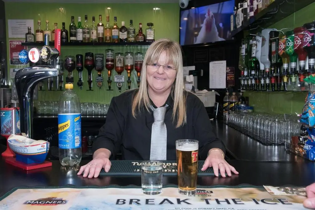 a woman sitting at a bar with a glass of beer at The Davron Hotel in Fraserburgh