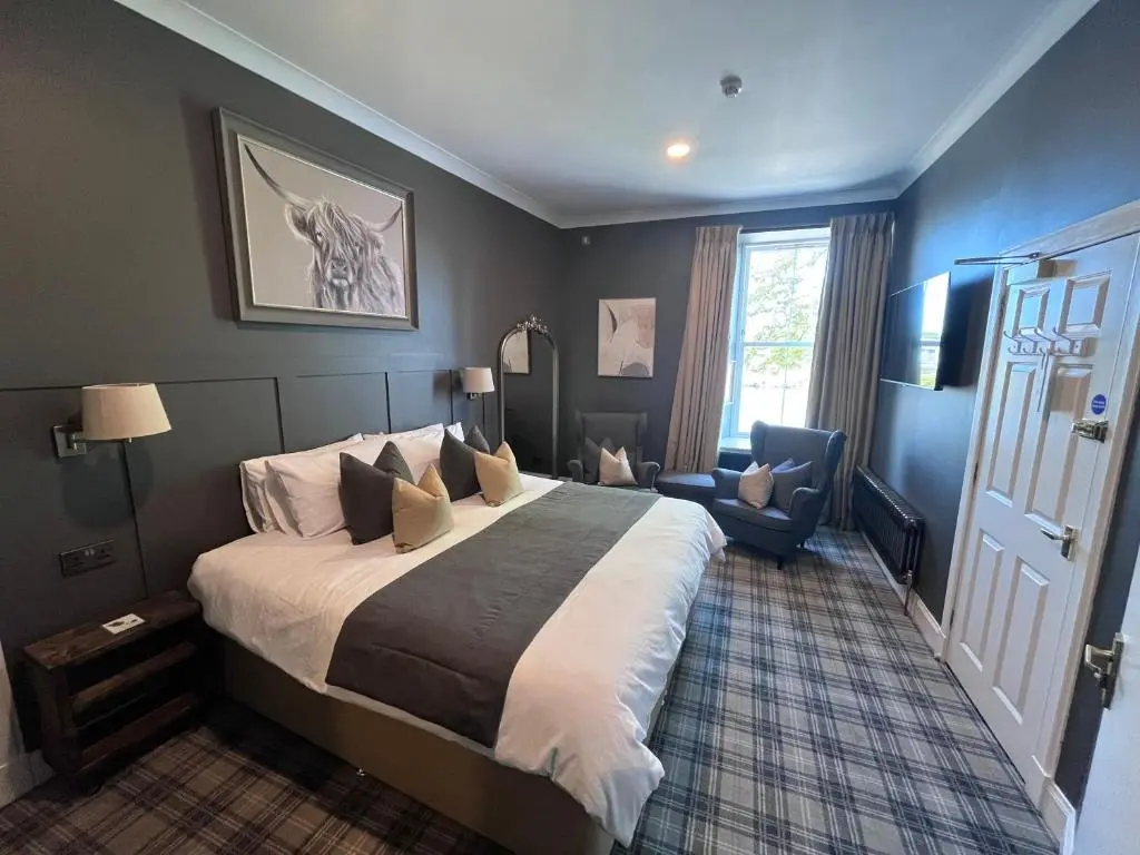 a bedroom with a bed and a chair and a window at Fraser House in Inverness