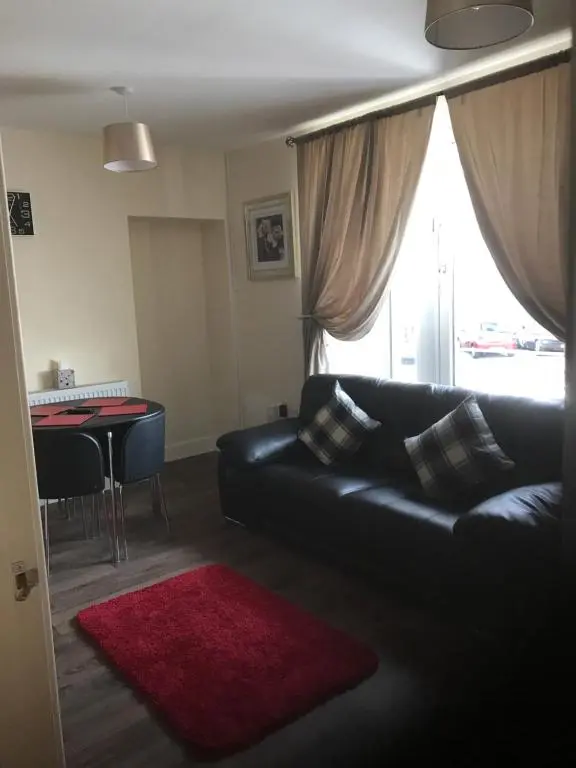 a living room with a black leather couch and a red rug at River Ness Apartments in Inverness