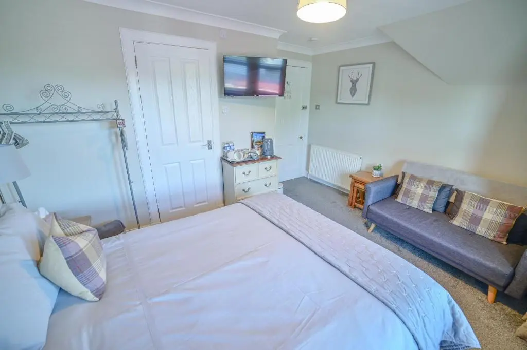 a bedroom with a large bed and a couch at Kylelachin in Dingwall