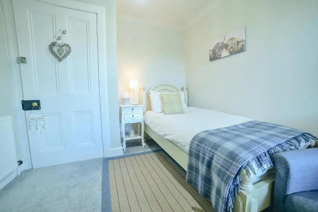 a small bedroom with a bed and a door with aoit at Kylelachin in Dingwall