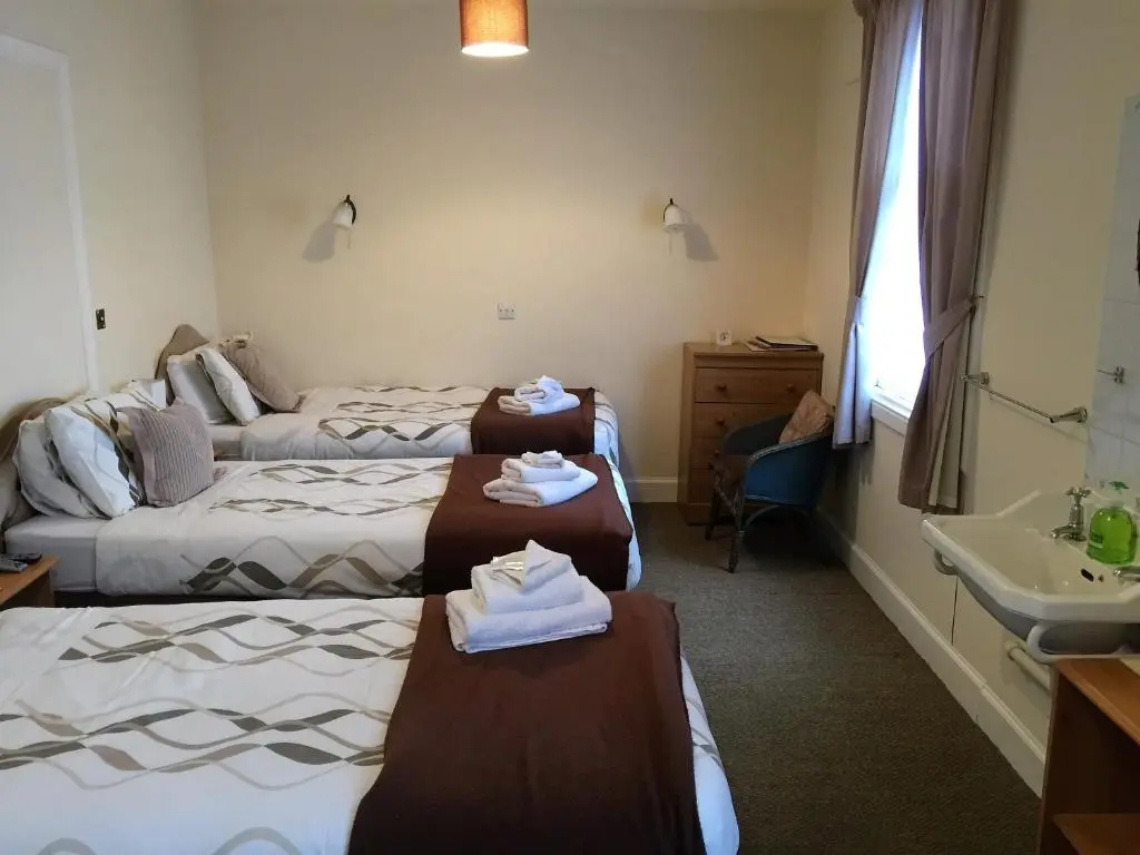 a hotel room with two beds and a sink at Belgrave Arms Hotel in Helmsdale