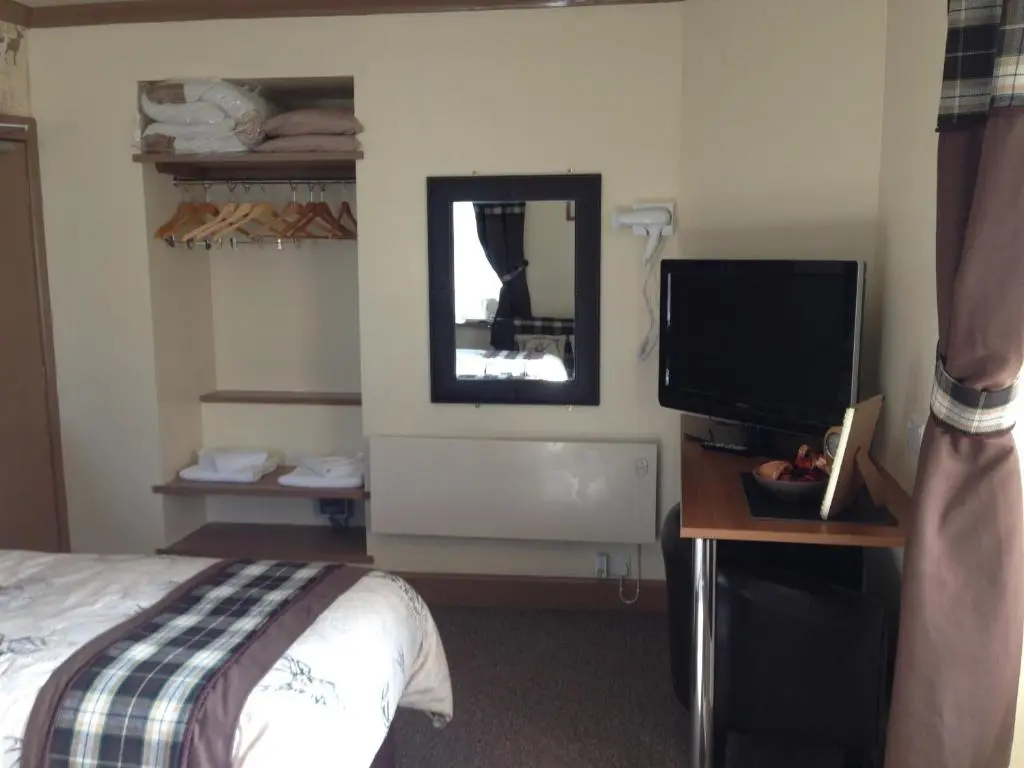 a hotel room with a bed and a television at Belgrave Arms Hotel in Helmsdale