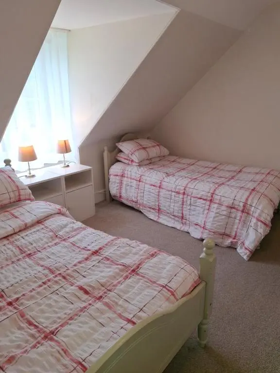 a attic bedroom with two beds and a window at Aberlour Cottages - Bolthole & Retreat in Aberlour