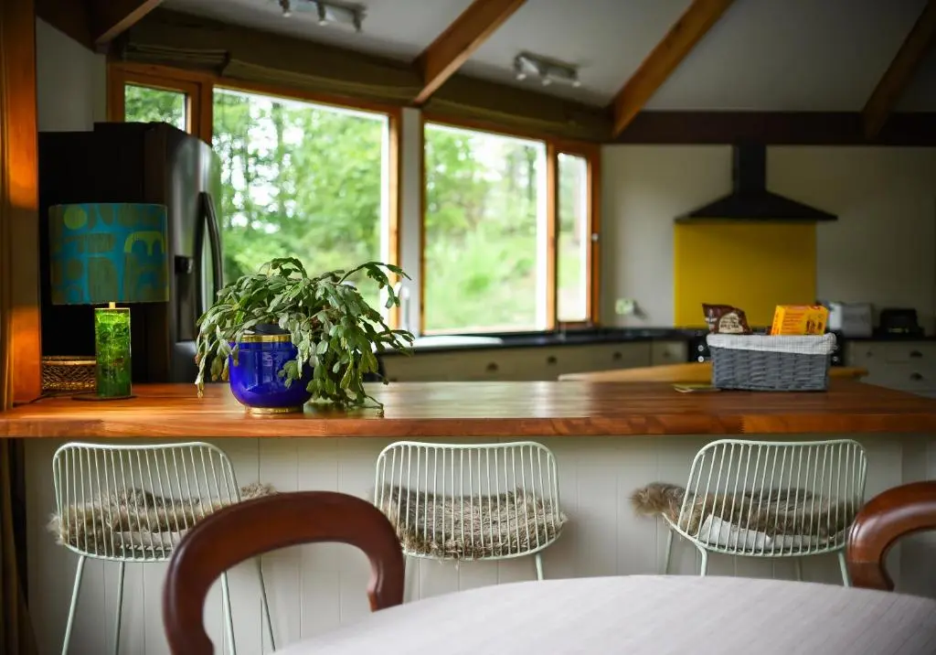 a kitchen with a counter with three chairs and a table at Cairngorm Lodge Rothiemurchus in Aviemore