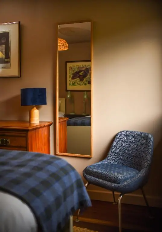 a bedroom with a blue chair and a mirror at Cairngorm Lodge Rothiemurchus in Aviemore
