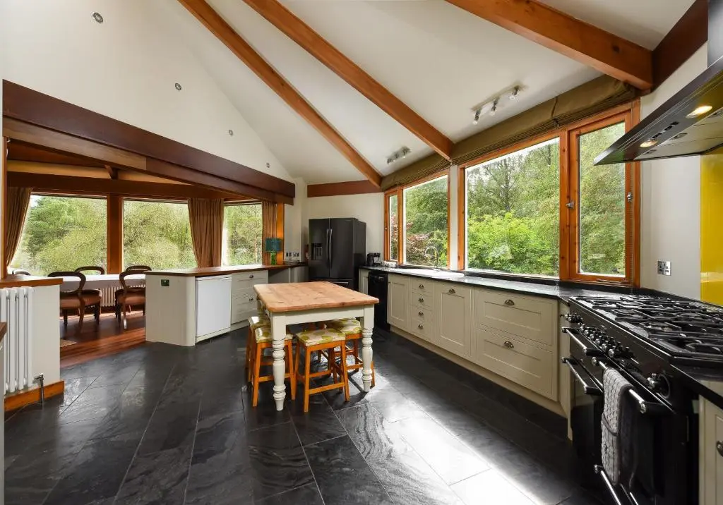 a kitchen with a stove and a table in it at Cairngorm Lodge Rothiemurchus in Aviemore