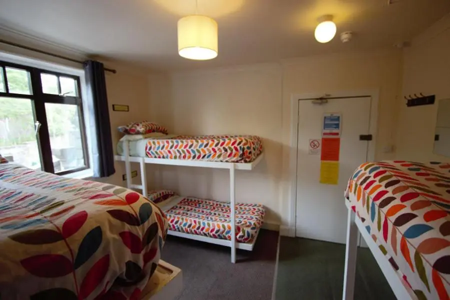 a room with two beds and a shelf and a window at Inverness Student Hotel in Inverness