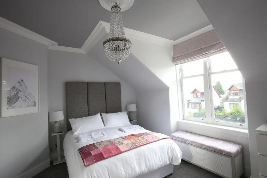 a white bedroom with a bed and a window at High Terrace Apartment in Boat of Garten