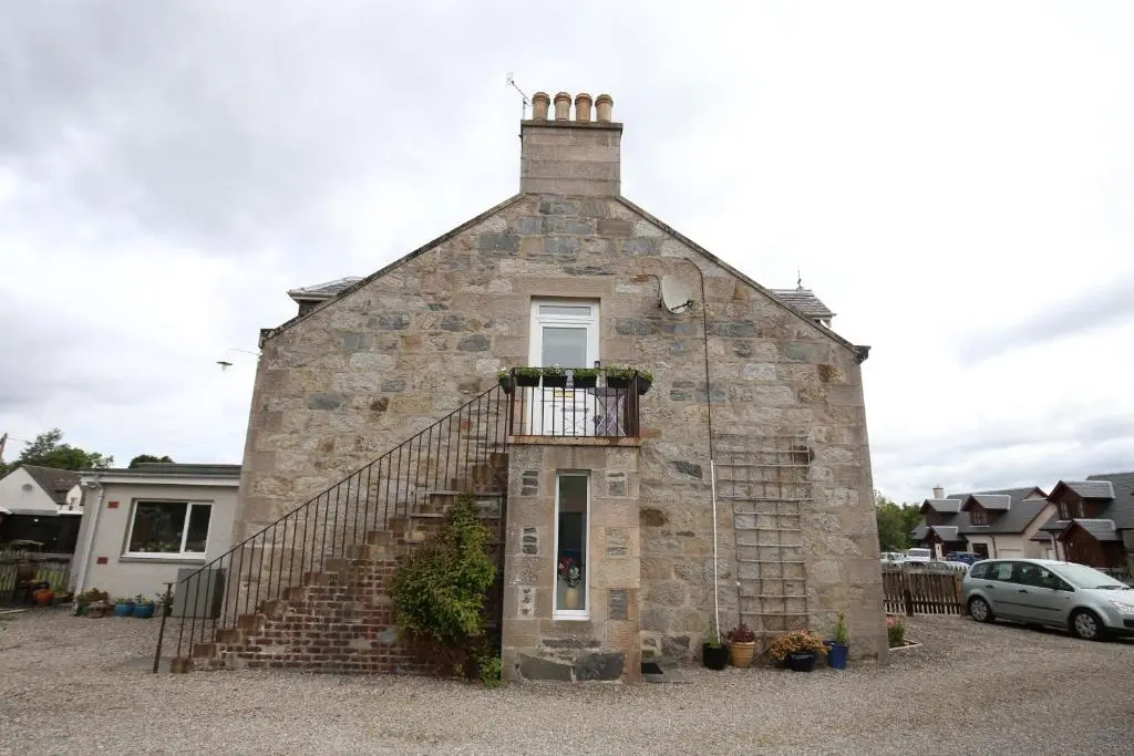 an old stone building with a staircase on it at High Terrace Apartment in Boat of Garten