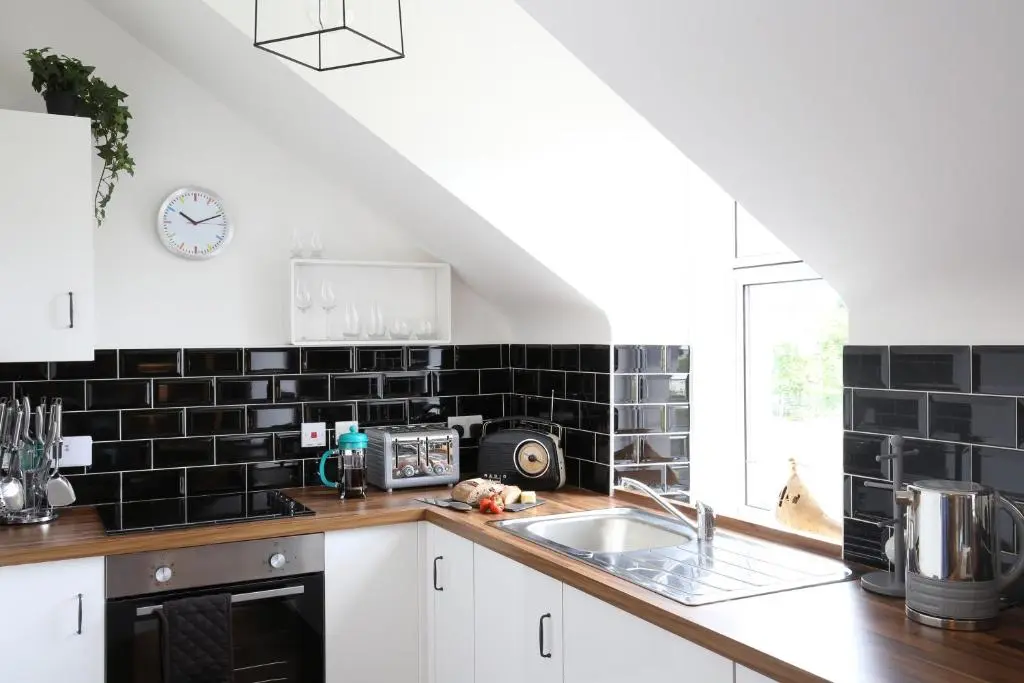 a kitchen with black tiles on the wall and a sink at High Terrace Apartment in Boat of Garten