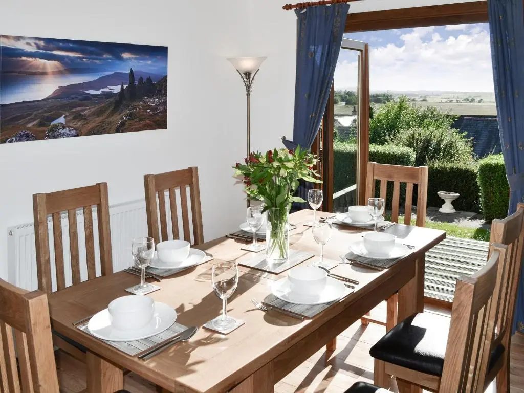 a dining room with a wooden table and a large window at Auldfield in Lhanbryd