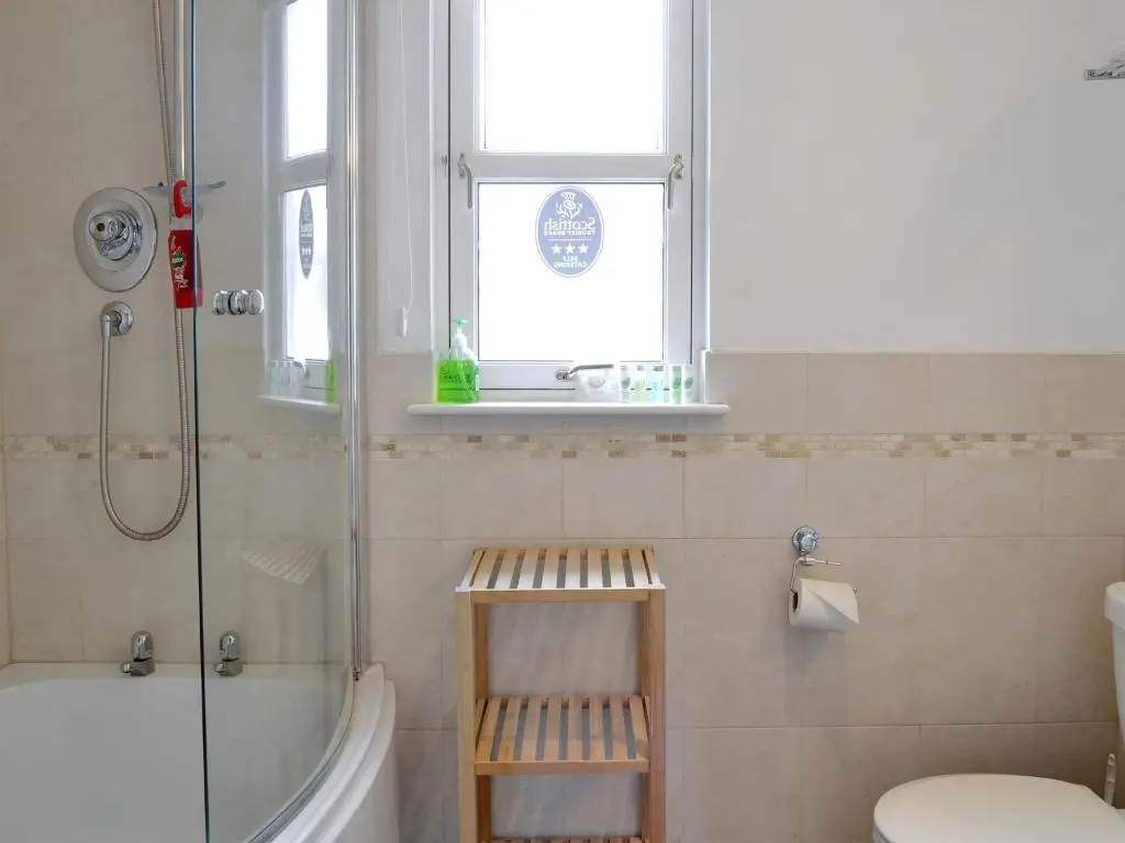 a bathroom with a shower and a toilet and a window at 32 Queens Court in Inchmarlo