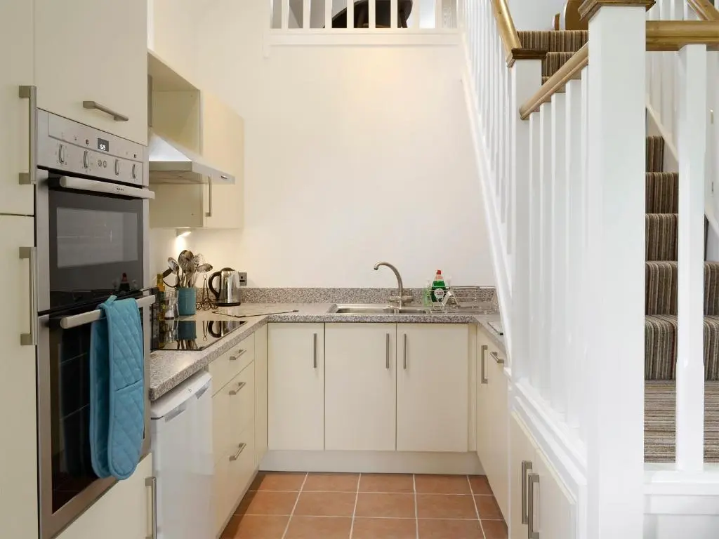 a kitchen with white cabinets and a staircase at The Barn in Ankerville