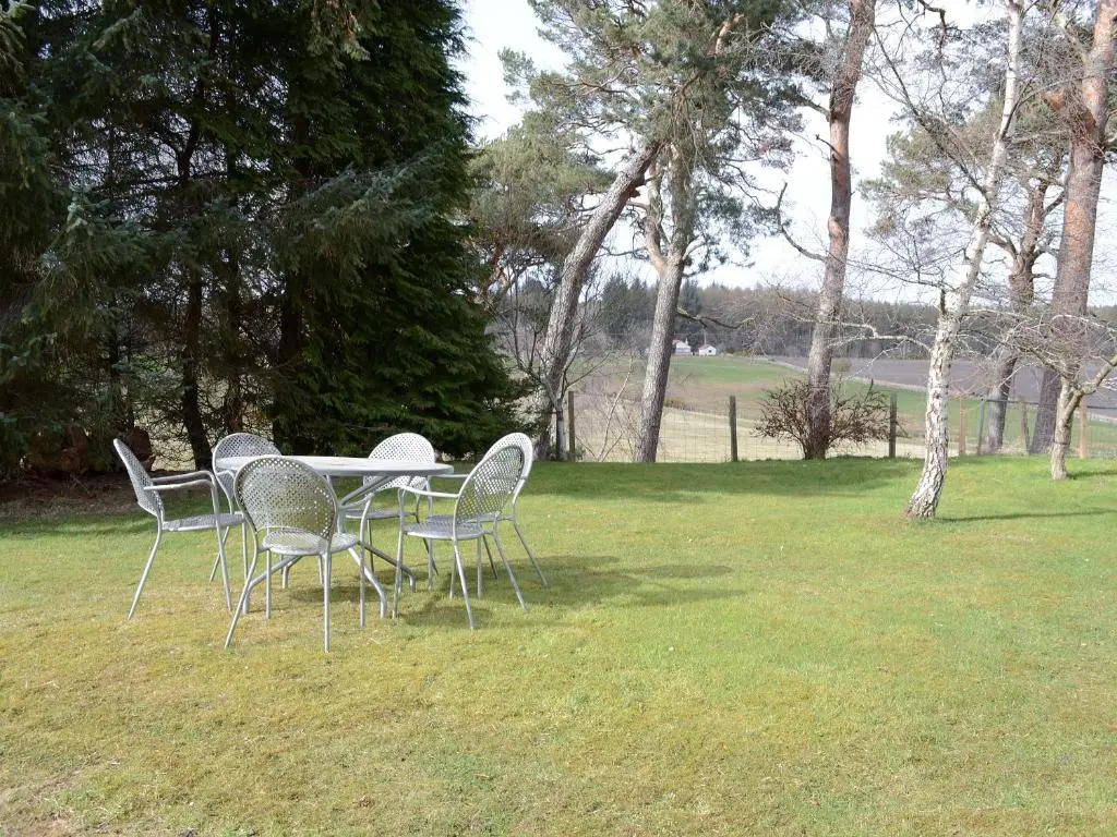 a table and chairs in a field with trees at The Barn in Ankerville