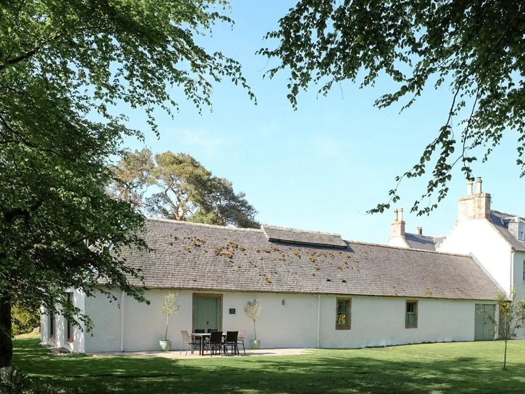 a white house with a table and chairs in front of it at The Barn in Ankerville