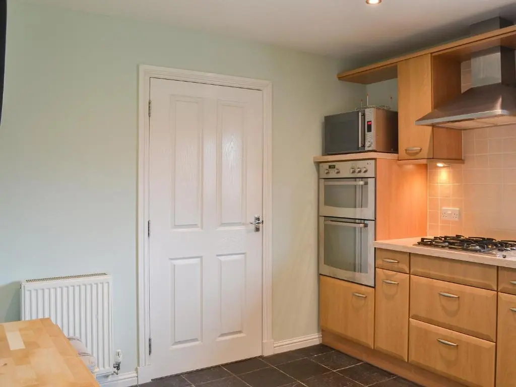 a kitchen with wooden cabinets and a white door at Stags Neuk in Aviemore