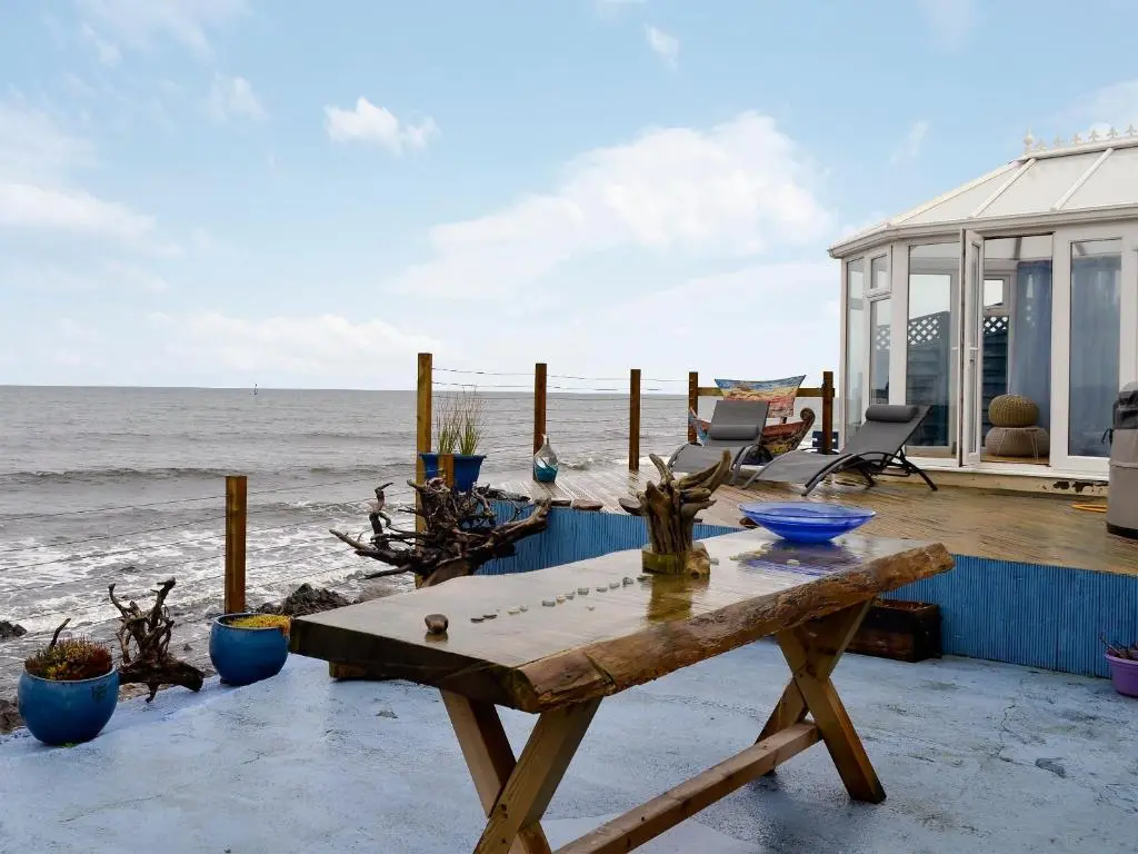 a wooden table sitting on a deck next to the ocean at Sea Yonder in Buckie