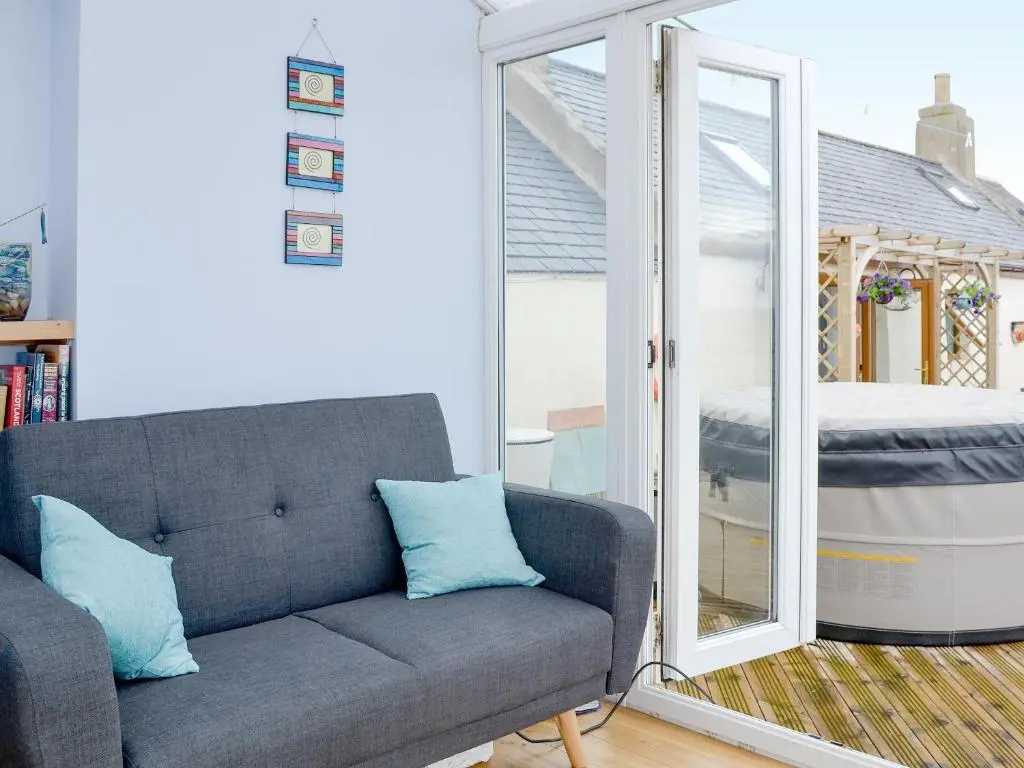 a living room with a couch and a sliding glass door at Sea Yonder in Buckie