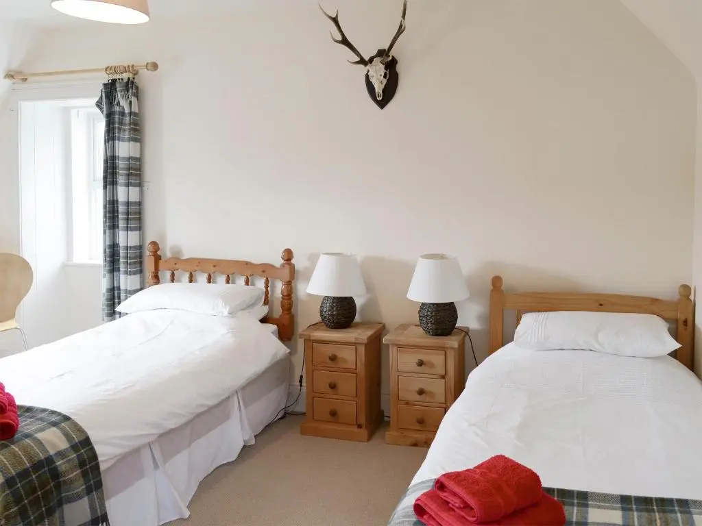 a bedroom with two beds and two lamps on night stands at Keeper's House in Glenrossal