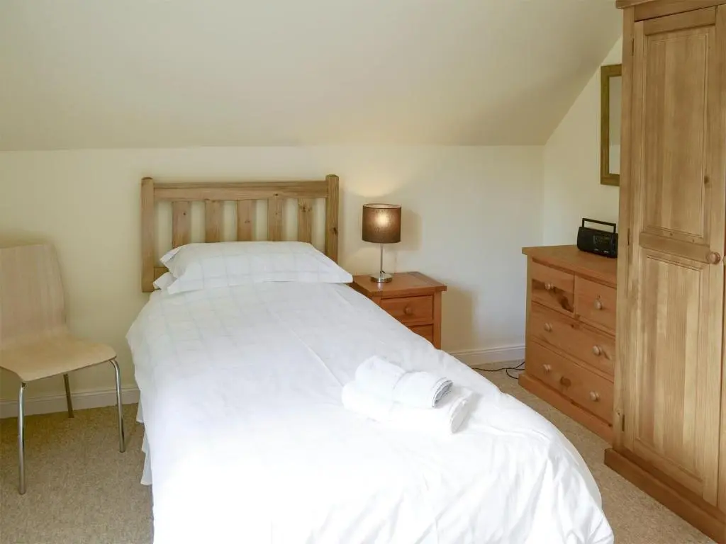 a bedroom with a large white bed and a dresser at Birch Cottage in Glenrossal