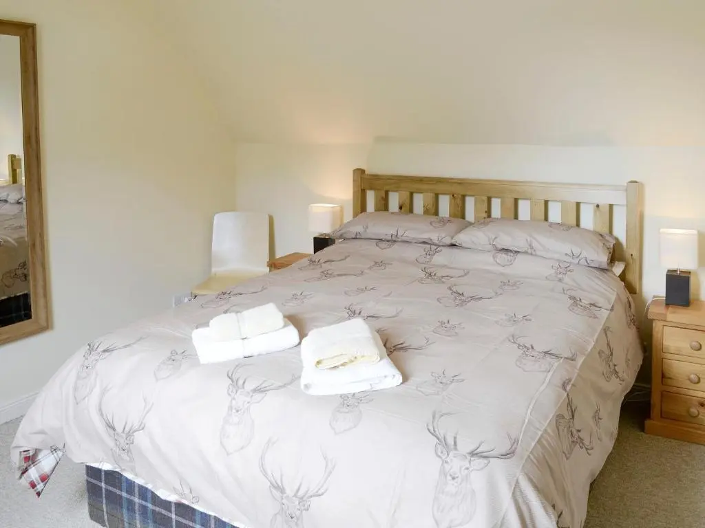 a bedroom with a bed with two towels on it at Rowan Cottage in Glenrossal