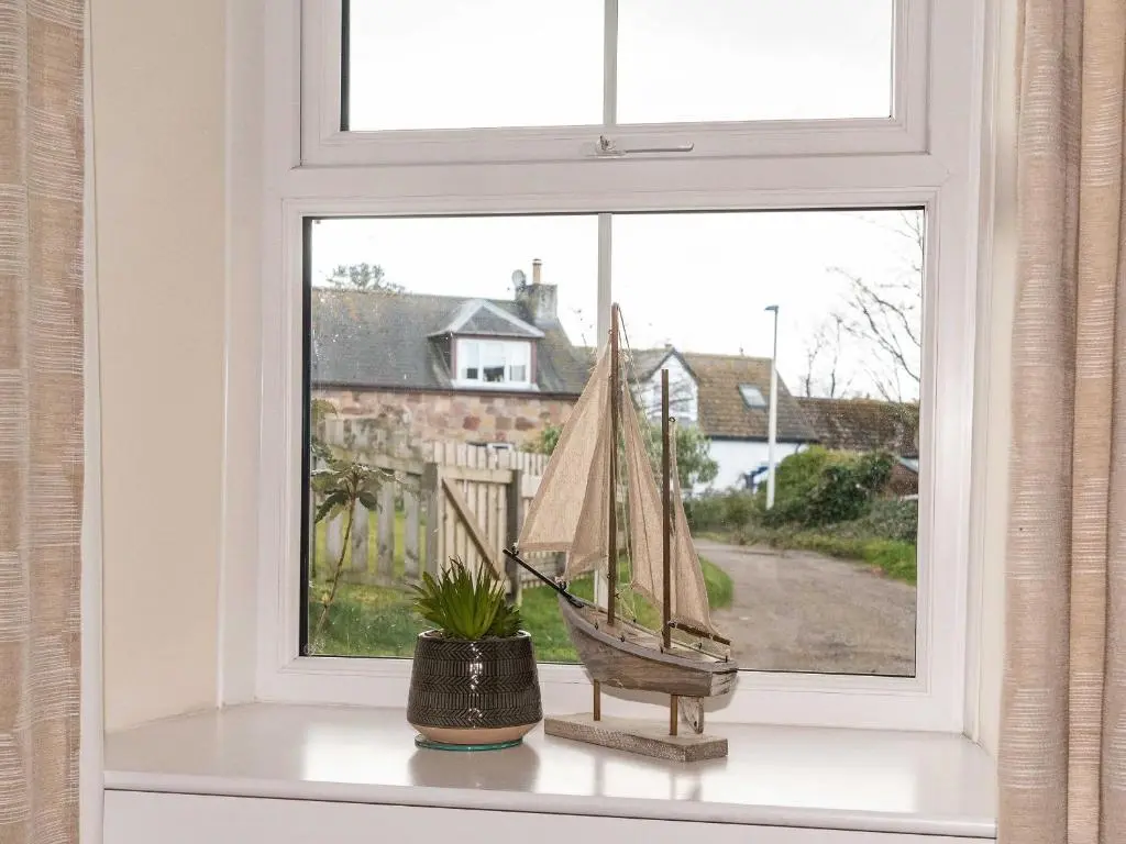 a window with a toy boat on a window sill at Rosslyn Cottage in Portmahomack